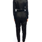 Faux silk jumpsuit with a cross over front, tapered leg, long sleeves, elasticized, tie waist and pockets in black