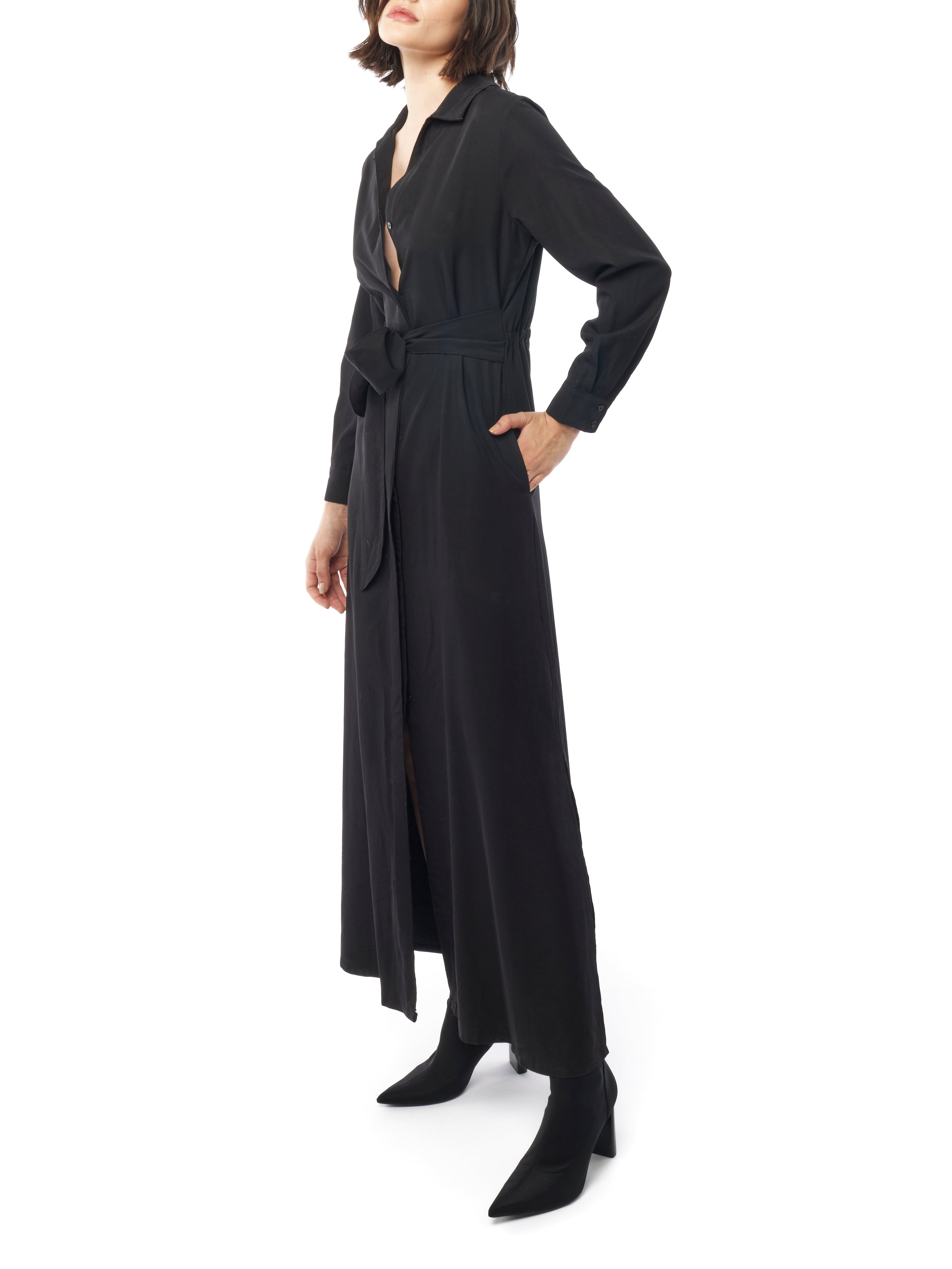 Long collared black dress with button down front, long cuffed sleeves and pockets. Side view 2