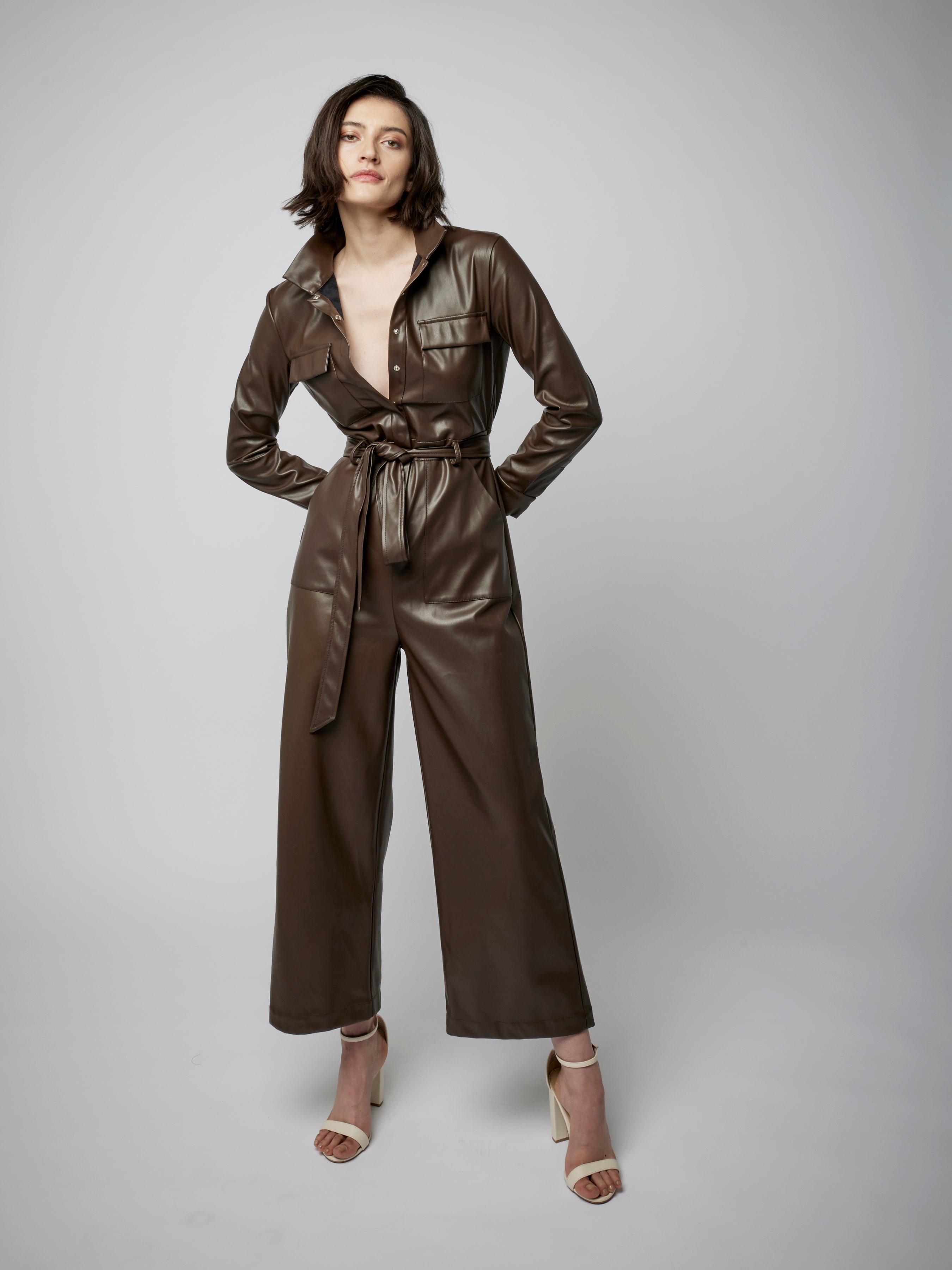 faux leather jumpsuit with long sleeves, wide legs, snap front, pockets and waist tie and elastic waist in maple