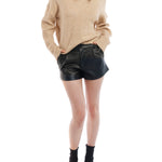 Faux leather, mid-rise shorts with a pleated front paired with a knit sweater