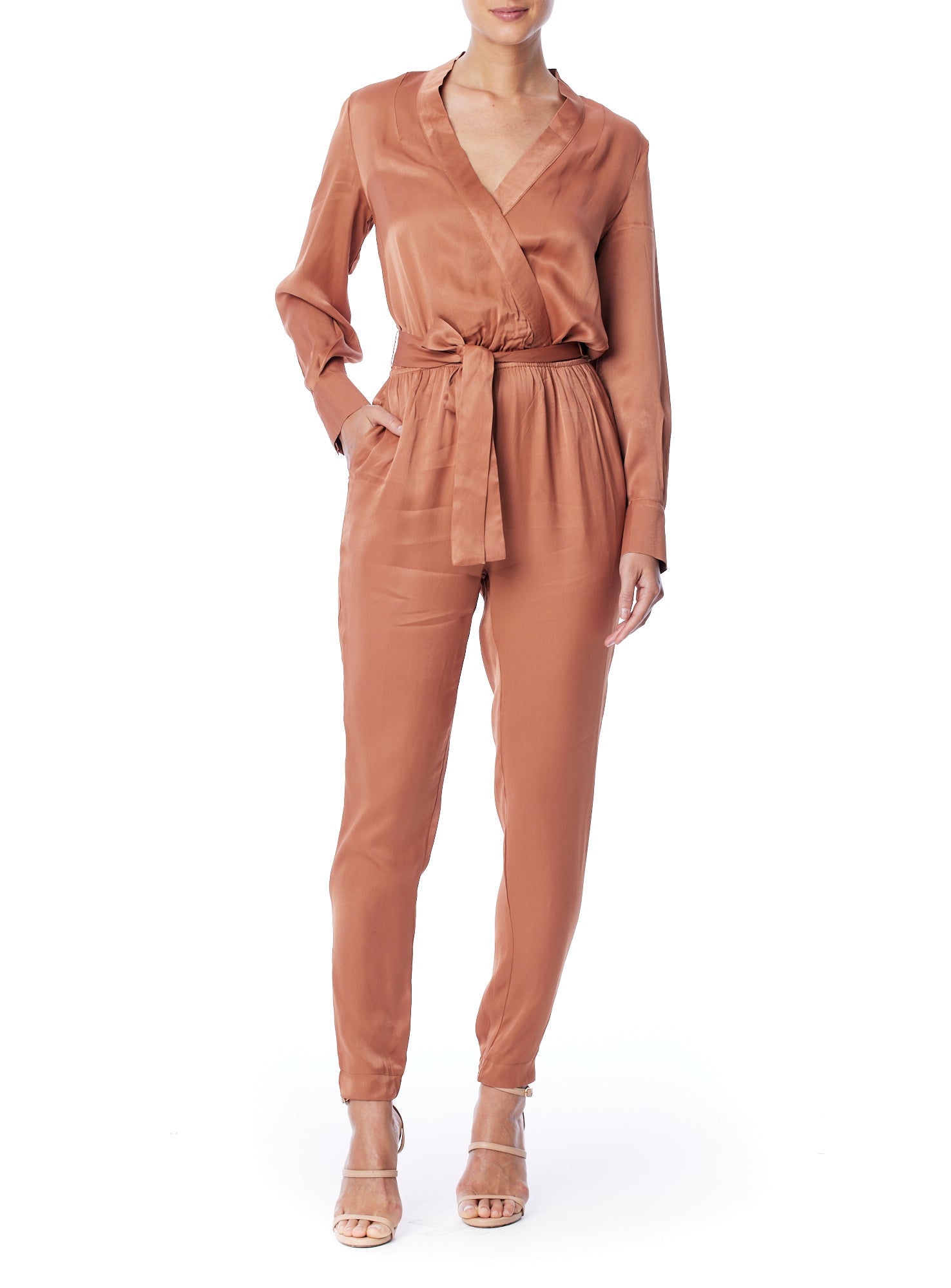 Faux silk jumpsuit with a cross over front, tapered leg, long sleeves, elasticized, tie waist and pockets in rust